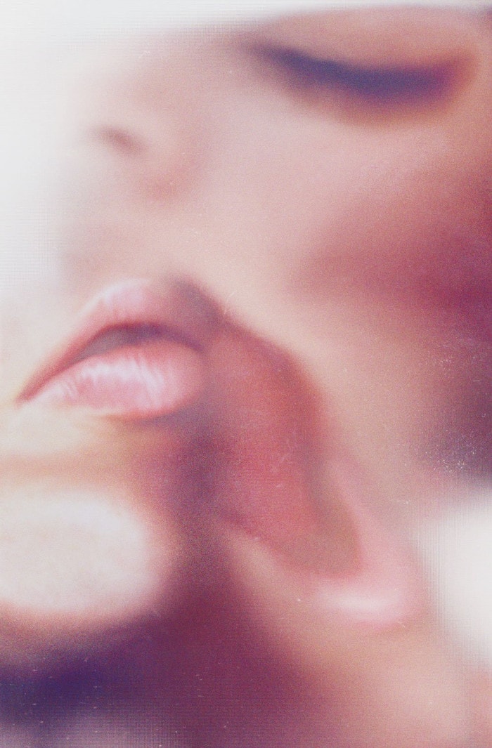 A woman’s lips and closed eyes are smudged against scanner glass.