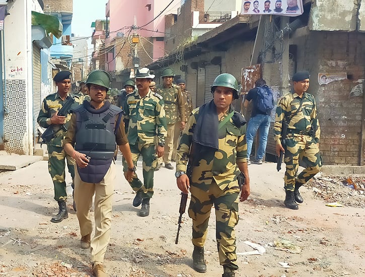 Photograph of Indian police walking through a neighborhood in Delhi