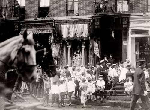 Photograph shows people gathered around a storefront shrine to the Black Madonna on East 13th Street.
