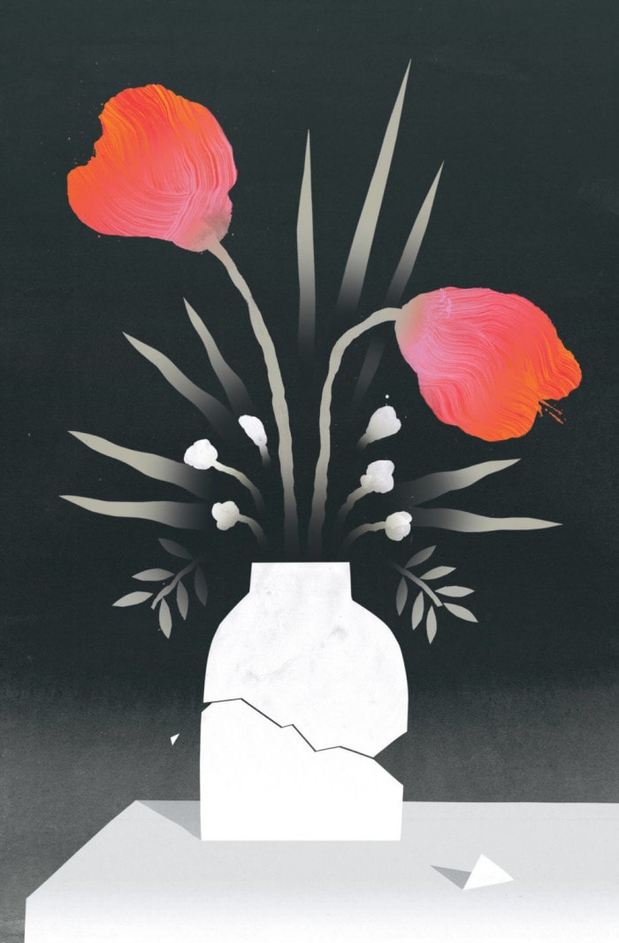 A broken vase holds two red flowers and six white flowers.