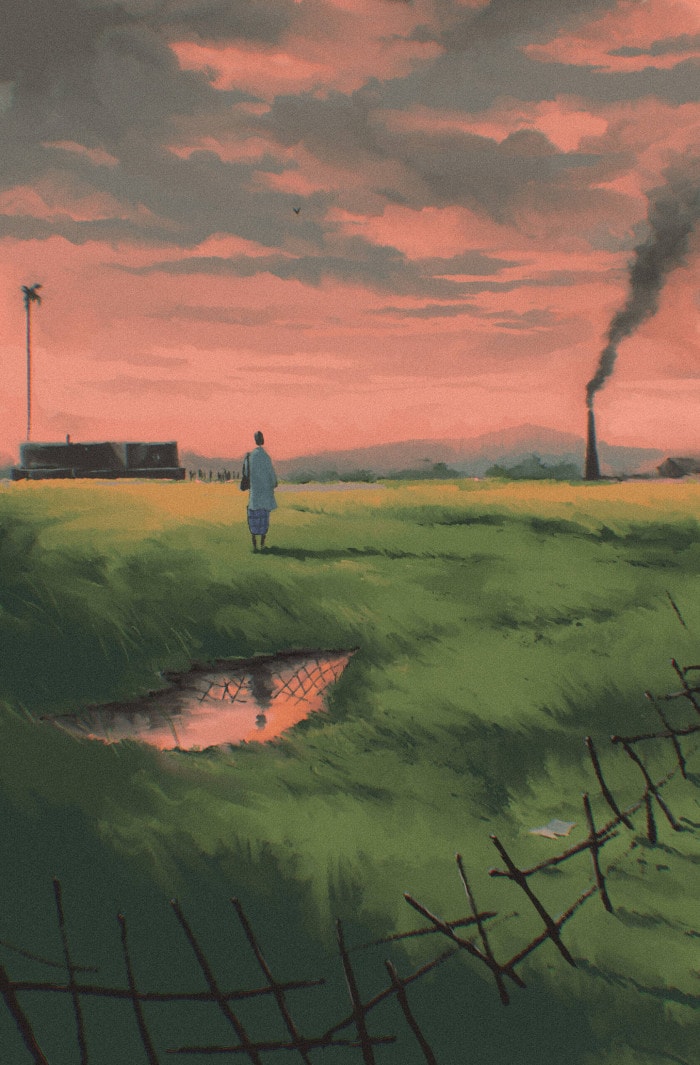 A man stands in a field surrounded by a broken fence at twilight. A chimney stack puffs smoke into the air at a distance. He is wearing a kurtha and dhoti, and is carrying a bag.